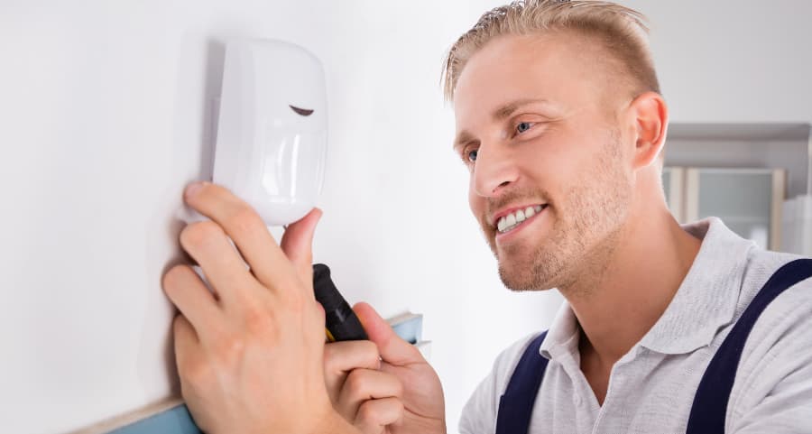 Man placing a motion sensor on a wall